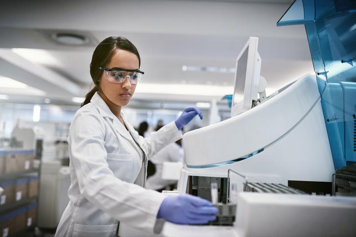 Shot of a young woman using a machine to conduct a medical test in a laboratory